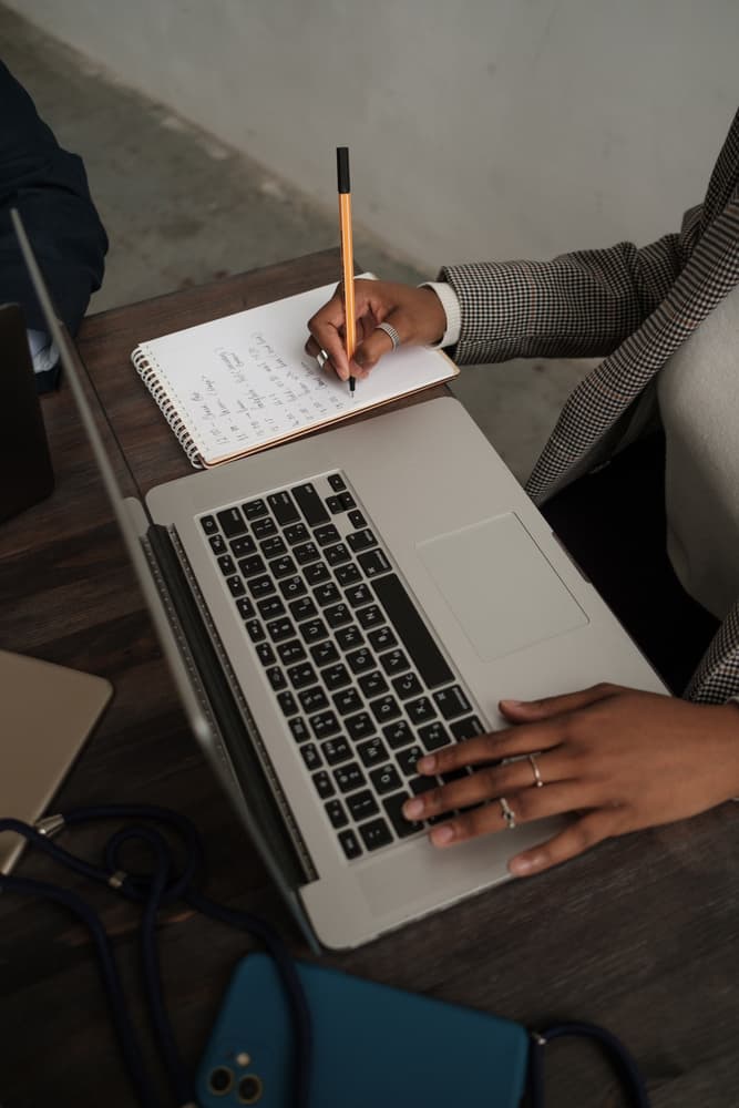 An overhead view of a laptop and notebook on a desk
